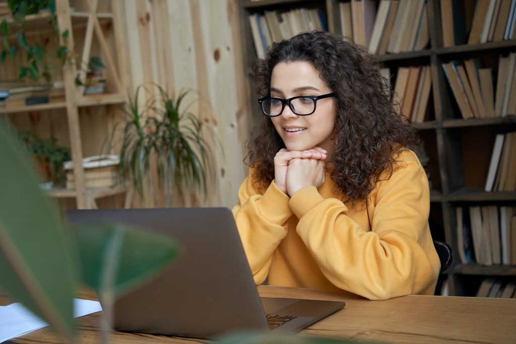 Hispanic teenage girl student watching online education webinar on laptop.